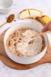 Mixing protein powder paste into cooked oats.