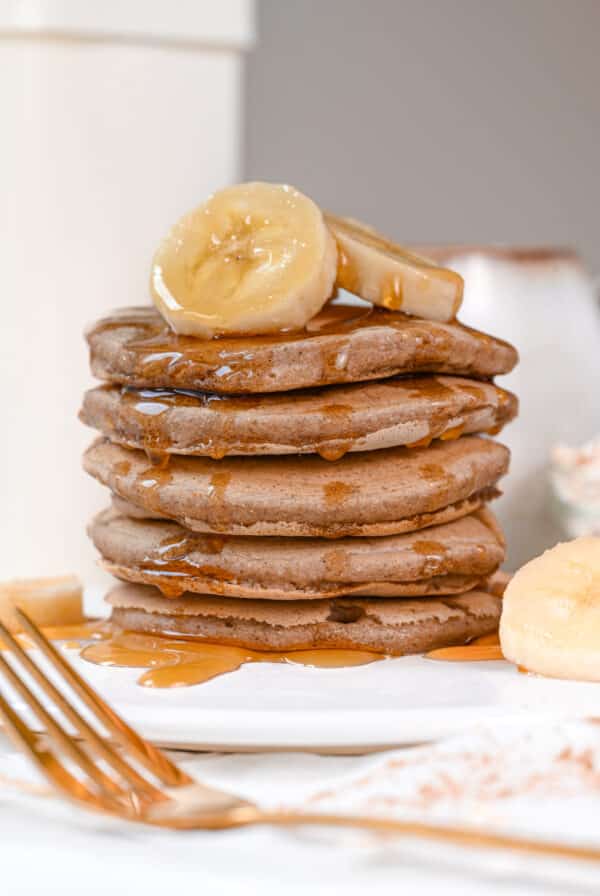 Stack of fluffy Oat Flour Pancakes with maple syrup and banana