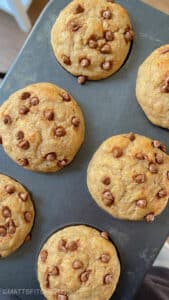 Healthy chocolate chips protein muffins after baking, in a lined muffin pan.