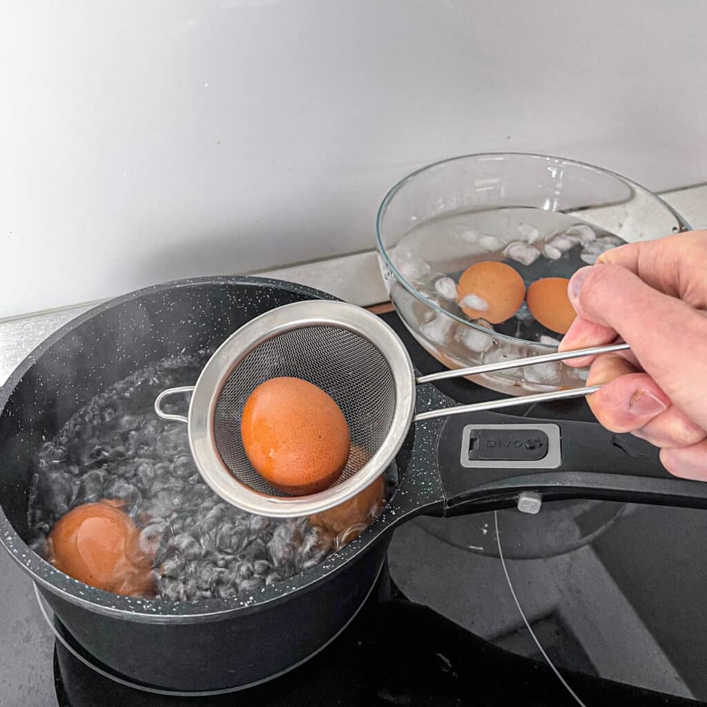 Removing boiled eggs from pot with skimmer