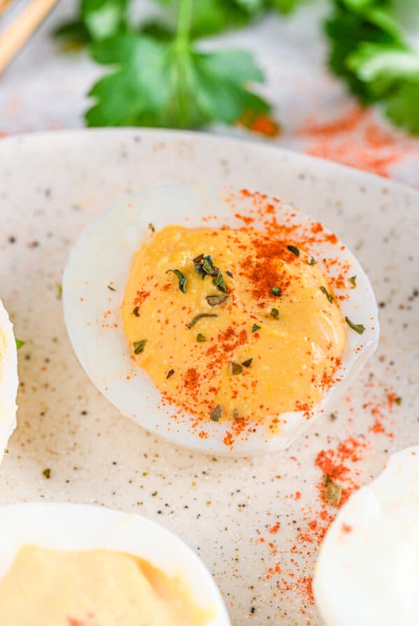 Cottage cheese deviled egg on a plate - A healthy deviled egg sprinkled with smoked paprika and dried herbs on a ceramic plate.