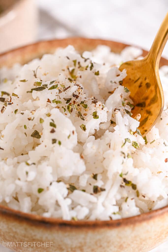 A golden fork scooping fluffy white rice garnished with spices.