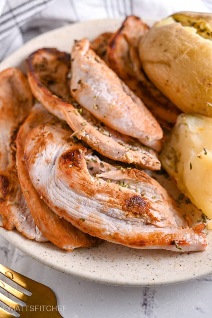 Turkey steak served with baked potatoes and seasoned with dried herbs