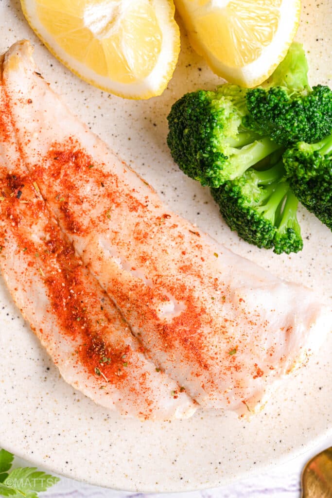 Baked cod with lemon and broccoli – Perfectly baked cod fillet with a golden seasoning crust, served with steamed broccoli and lemon wedges.