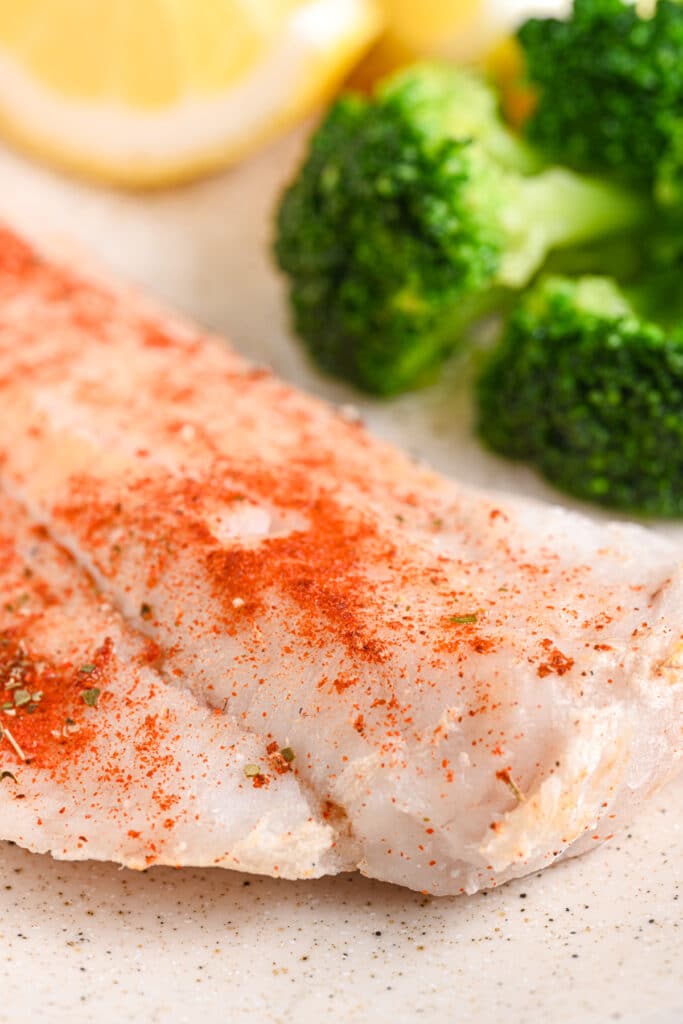 Close-up of baked cod fillet – Tender, flaky baked cod with red seasoning, highlighting its juicy texture.