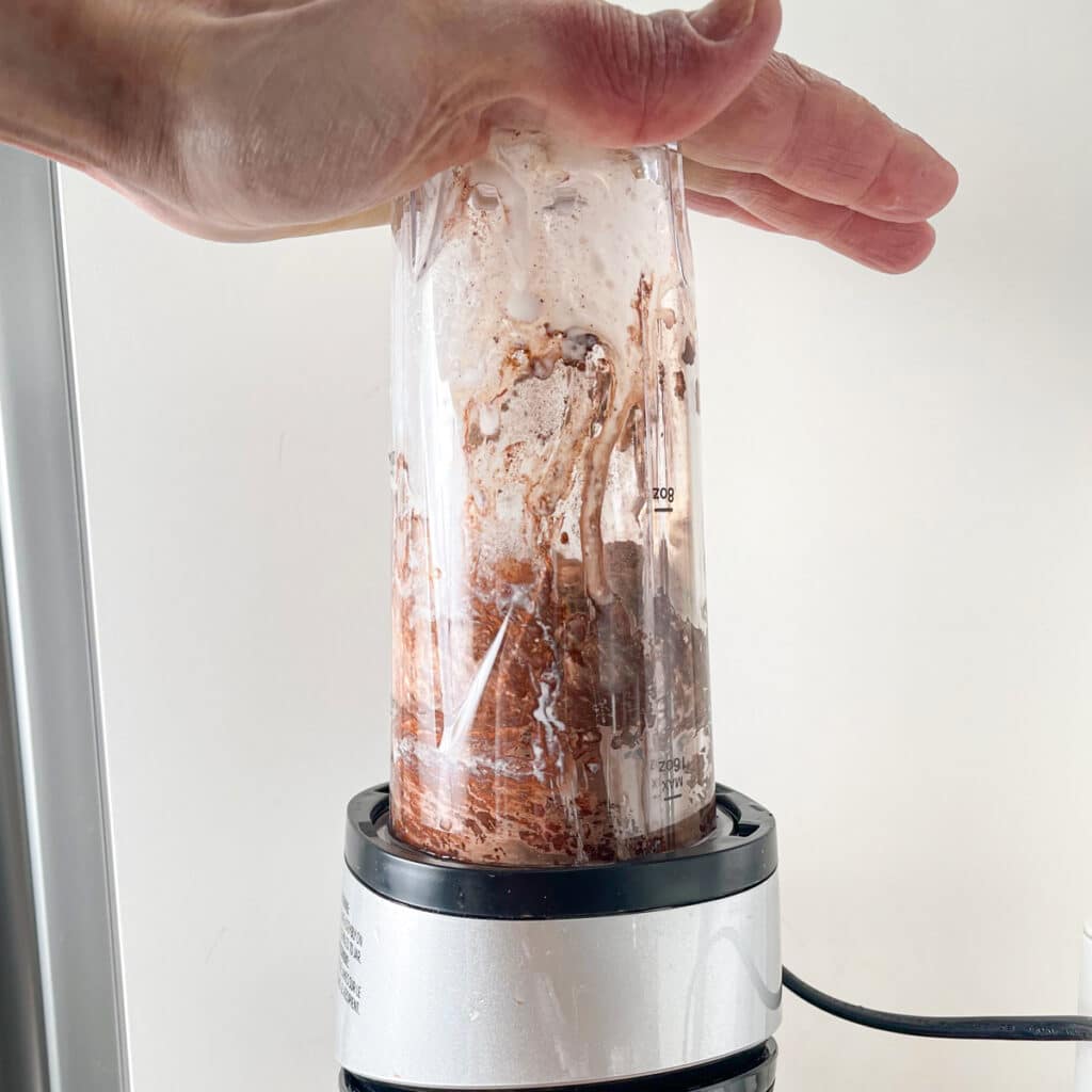 Blending cottage cheese with cocoa powder and maple syrup.