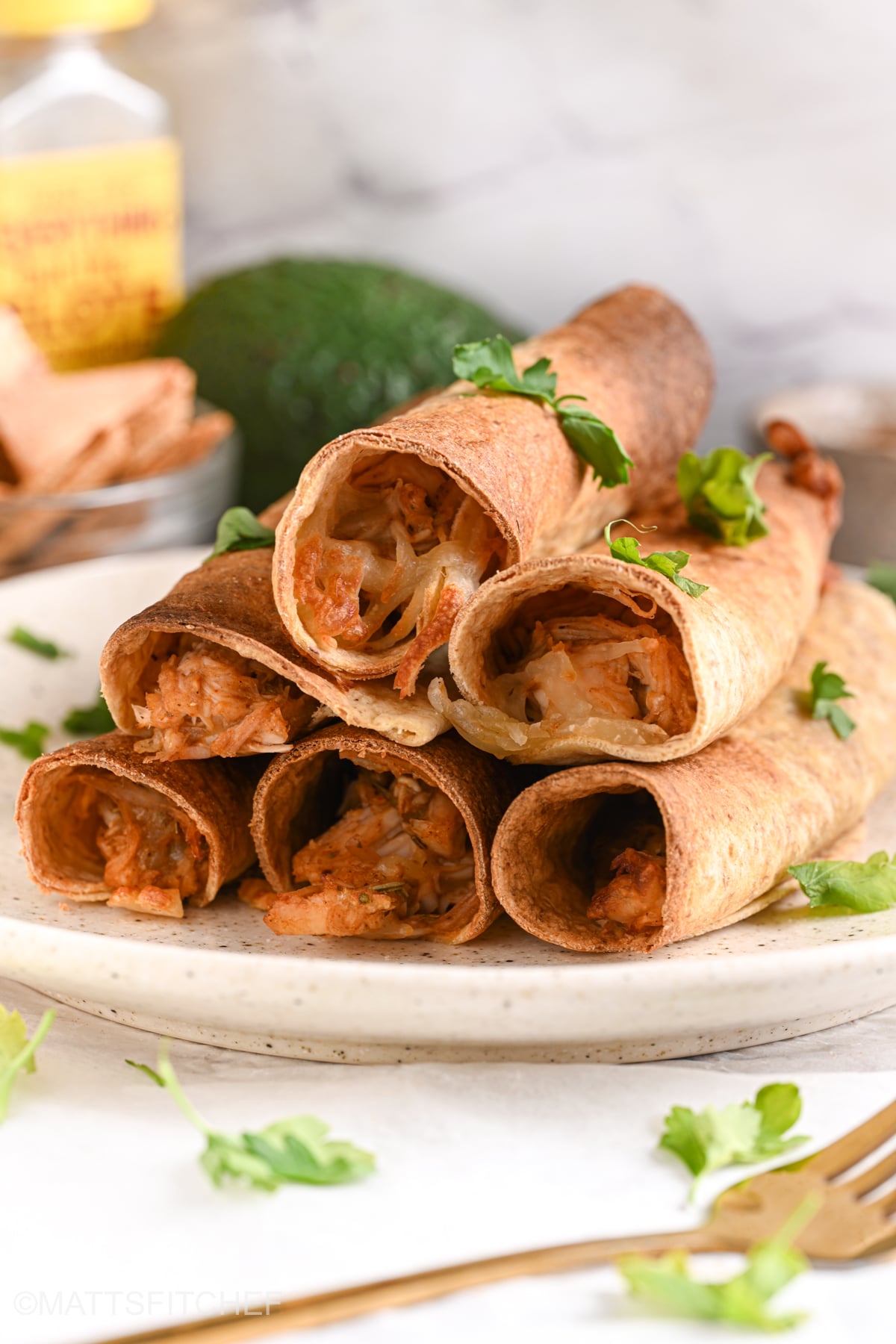 Front-facing plate of stacked chicken taquitos showing the savory cheesy chicken filling inside.