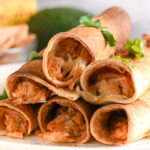 Close-up view of crispy baked chicken taquitos filled with shredded chicken and melted cheese.
