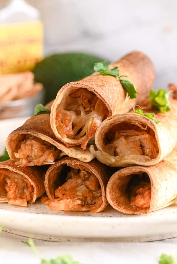 Close-up view of crispy baked chicken taquitos filled with shredded chicken and melted cheese.