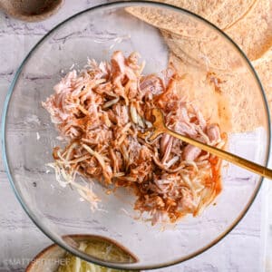 Stirring together shredded chicken, cheese, salsa, and spices to make the filling mixture.