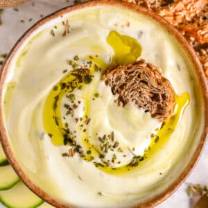 Thick and smooth whipped cottage cheese dip with golden olive oil, paired with crunchy seeded bread and fresh vegetables.