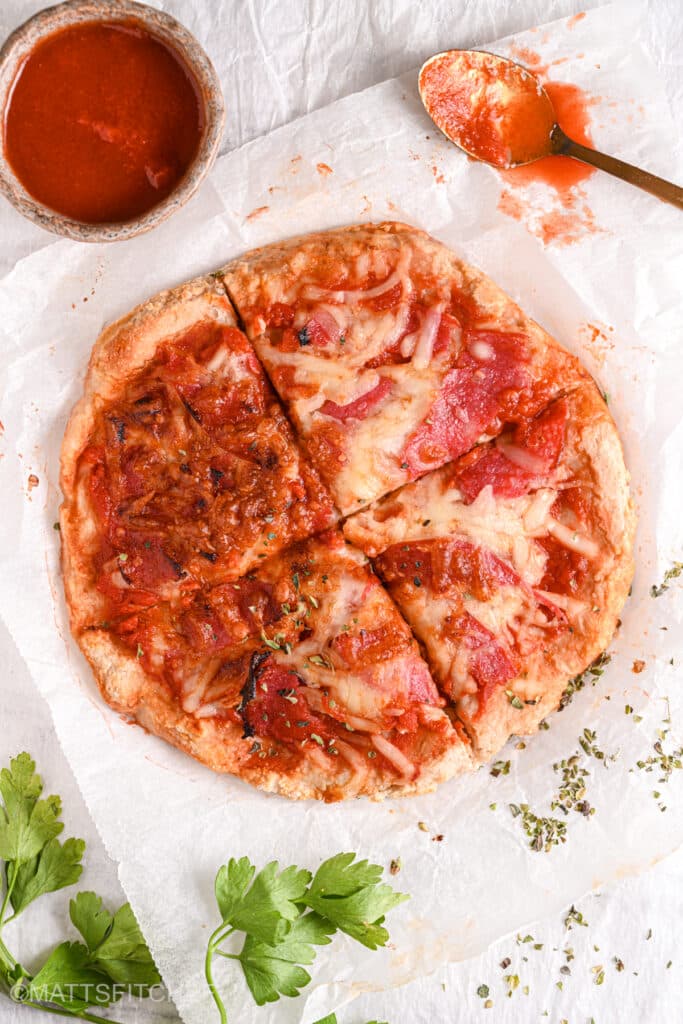 Slicing the protein pizza – A high-protein, low-carb pizza with a crispy crust being sliced and ready to serve.