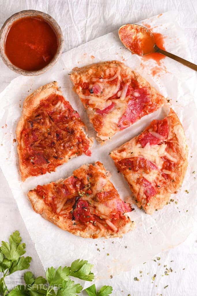 Sliced cottage cheese pizza – A crispy high-protein cottage cheese pizza crust cut into four slices, topped with turkey salami and melted mozzarella.