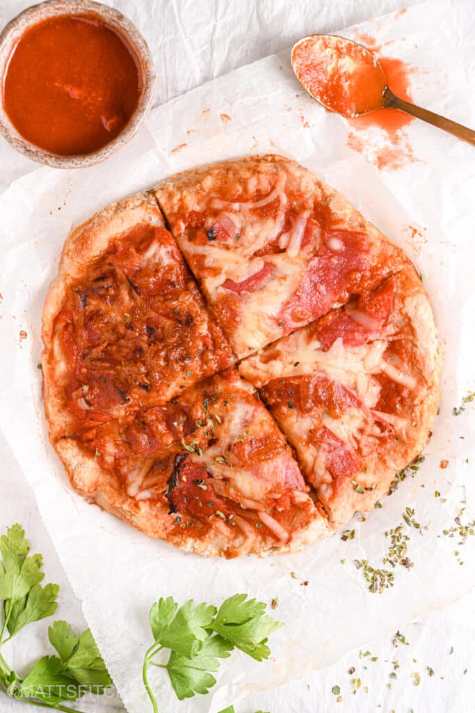 Slicing the protein pizza – A high-protein, low-carb pizza with a crispy crust being sliced and ready to serve.