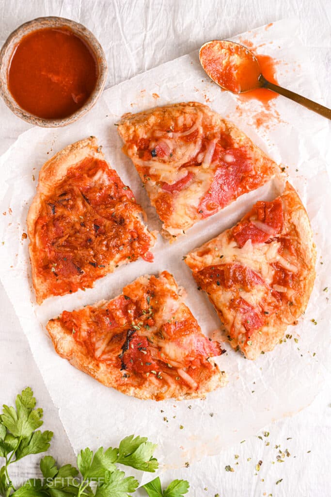 Sliced cottage cheese pizza – A crispy high-protein cottage cheese pizza crust cut into four slices, topped with turkey salami and melted mozzarella.