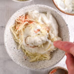 Mixing cottage cheese queso ingredients – A hand stirring the creamy cottage cheese, shredded cheese, and taco seasoning together.