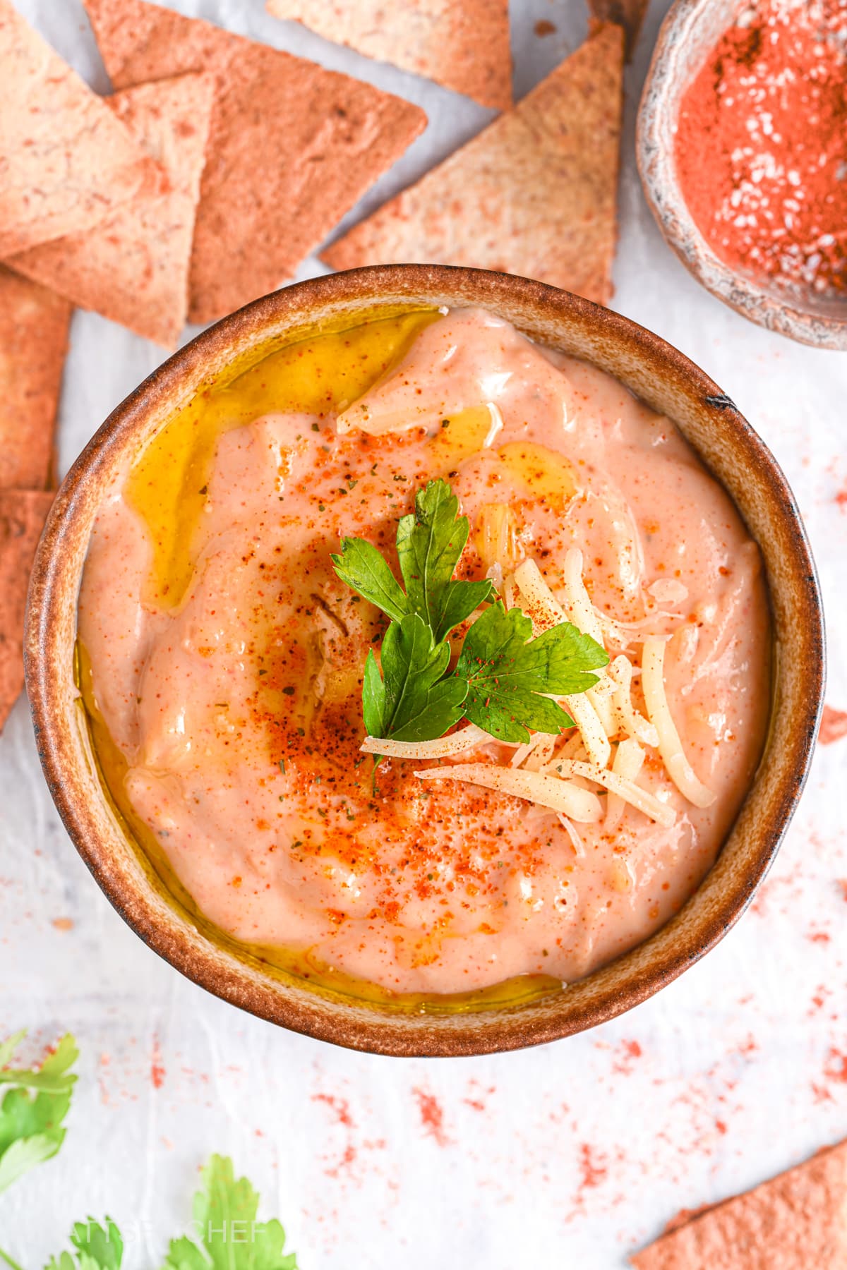 Finished cottage cheese queso with toppings &ndash; A smooth, cheesy queso dip garnished with fresh parsley and extra cheese.