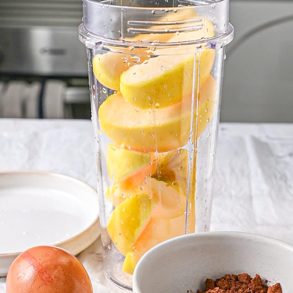 Sliced apples in a blender, ready to be blended for a healthy mug cake recipe.