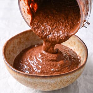 Smooth and rich chocolate mug cake batter being poured into a bowl.