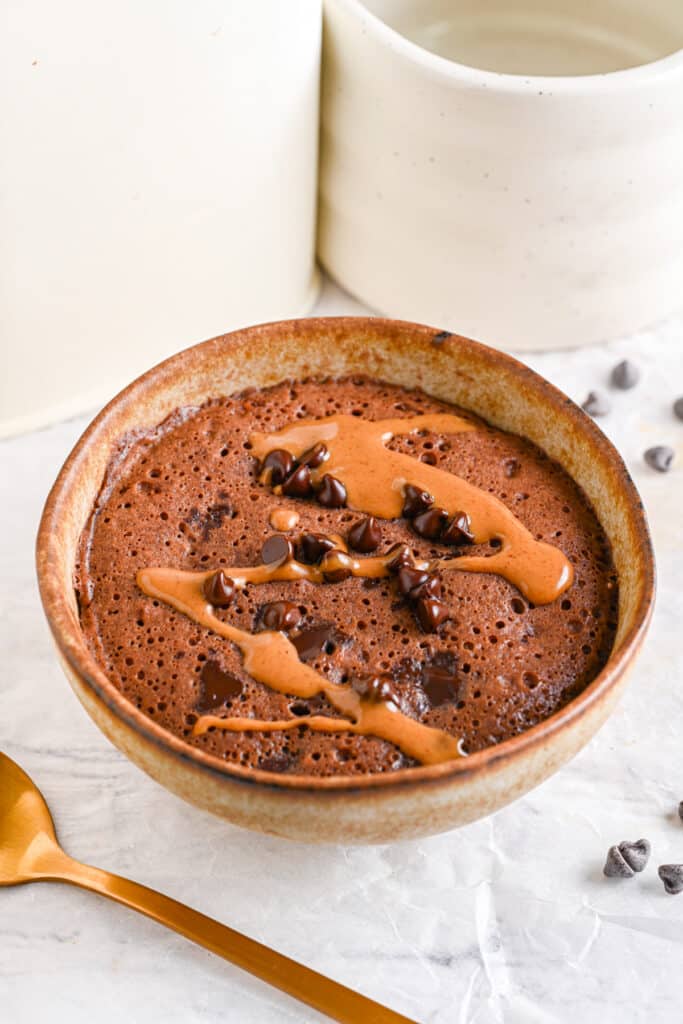 Freshly baked healthy chocolate mug cake with a gooey, fudgy texture in a ceramic bowl.