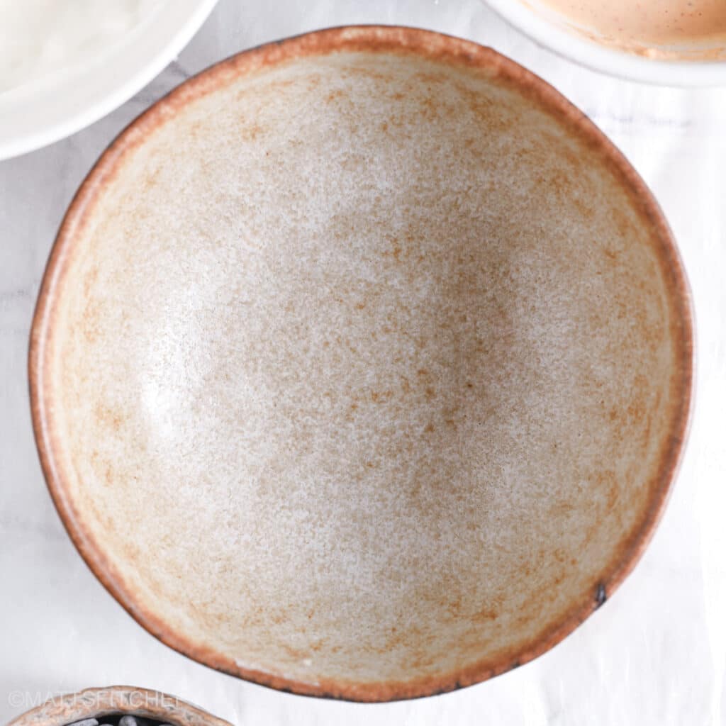 A clean, empty ceramic mixing bowl placed on a white surface, ready for ingredients.