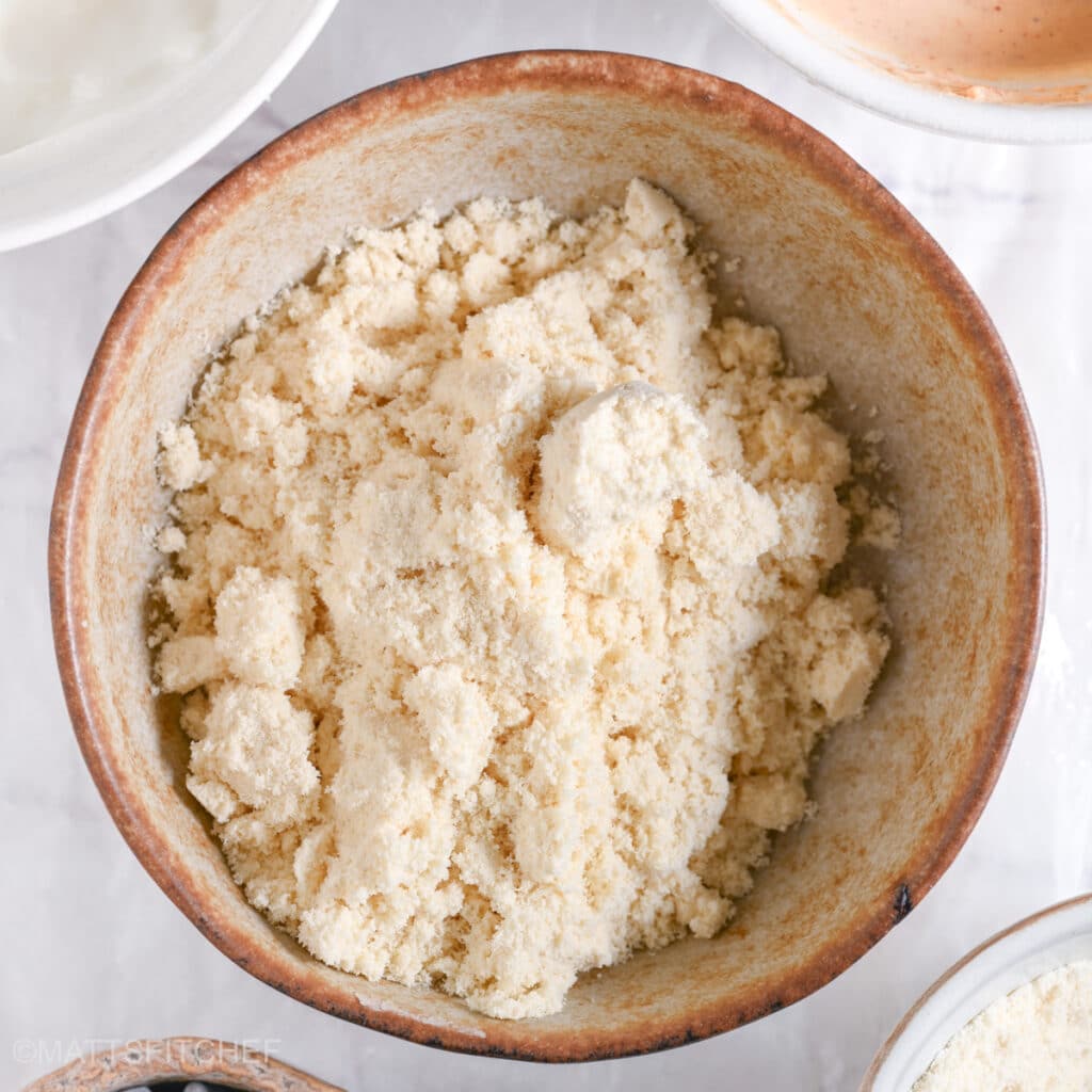 A ceramic bowl filled with vanilla protein powder, the base ingredient for protein cookie dough.