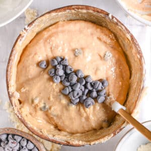 A smooth and creamy protein cookie dough being stirred in a bowl with a golden spoon.