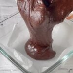 Transferring brownie batter to brownie pan for baking.