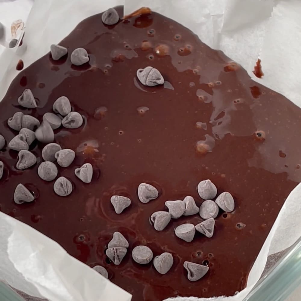 Sweet potato pancake batter in a baking pan topped with vegan chocolate chips.