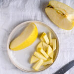 Golden apple cut into slices on a ceramic plate for healthy lentil salad prep