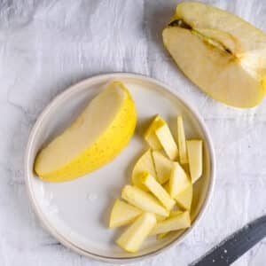 Golden apple cut into slices on a ceramic plate for healthy lentil salad prep