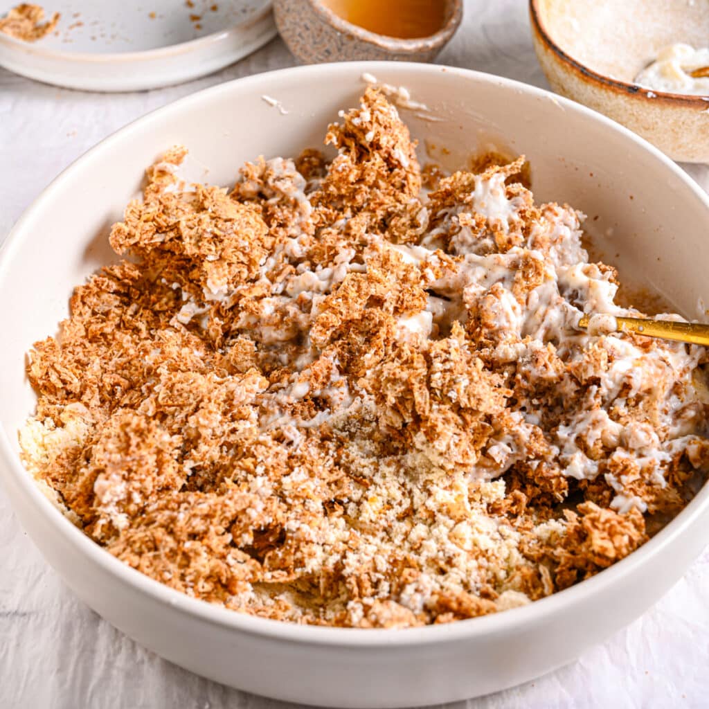 Mixing Weetabix, yogurt, and protein powder – A fork stirring together Weetabix, Greek yogurt, and protein powder for a thick and creamy consistency.