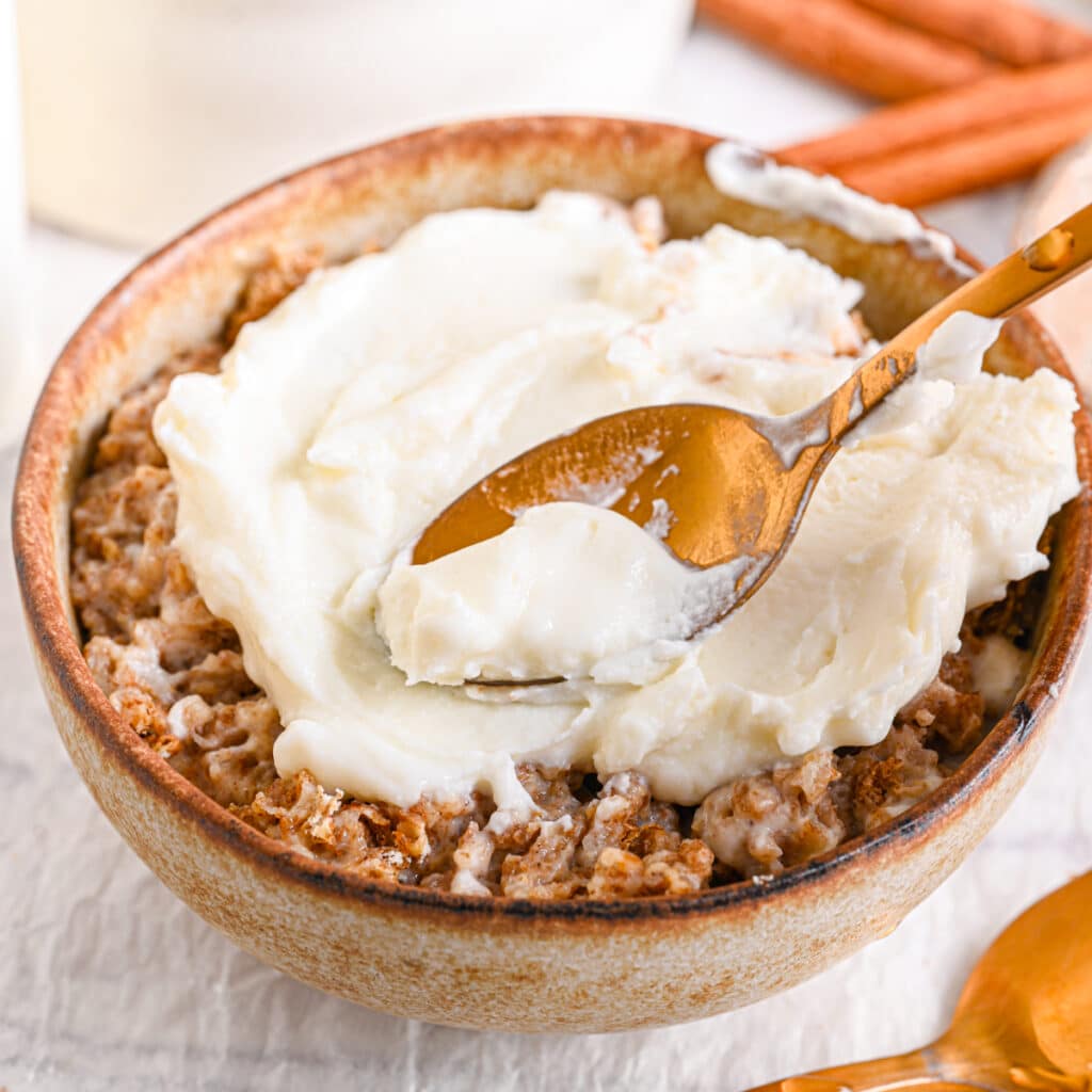 Spreading Greek yogurt over overnight Weetabix – A spoon smoothing a thick layer of Greek yogurt over the Weetabix mixture.