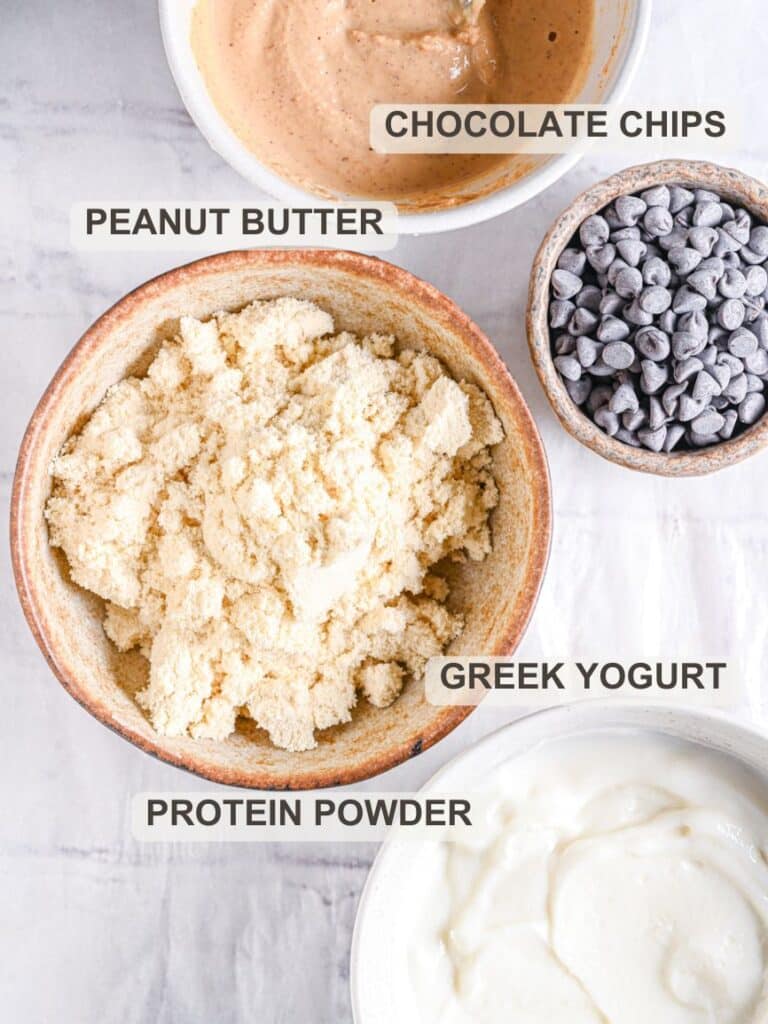 Ingredients for high protein cookie dough from the top - protein powder, Greek yogurt, peanut butter and chocolate chips.