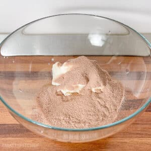 Greek yogurt topped with chocolate protein powder in a bowl, showing the simple two-ingredient mousse preparation.