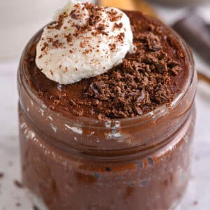 Finished chocolate protein mousse in a jar topped with whipped cottage cheese and shaved chocolate.