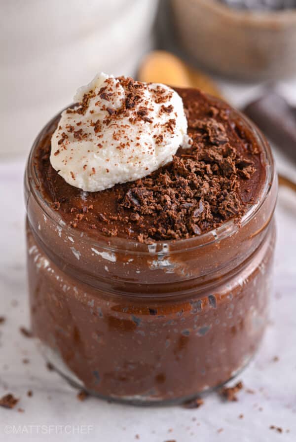 Finished chocolate protein mousse in a jar topped with whipped cottage cheese and shaved chocolate.