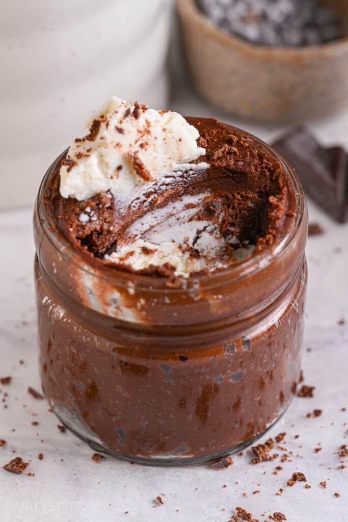 Partially eaten chocolate protein mousse in a jar, showing creamy and airy texture with cottage cheese topping.