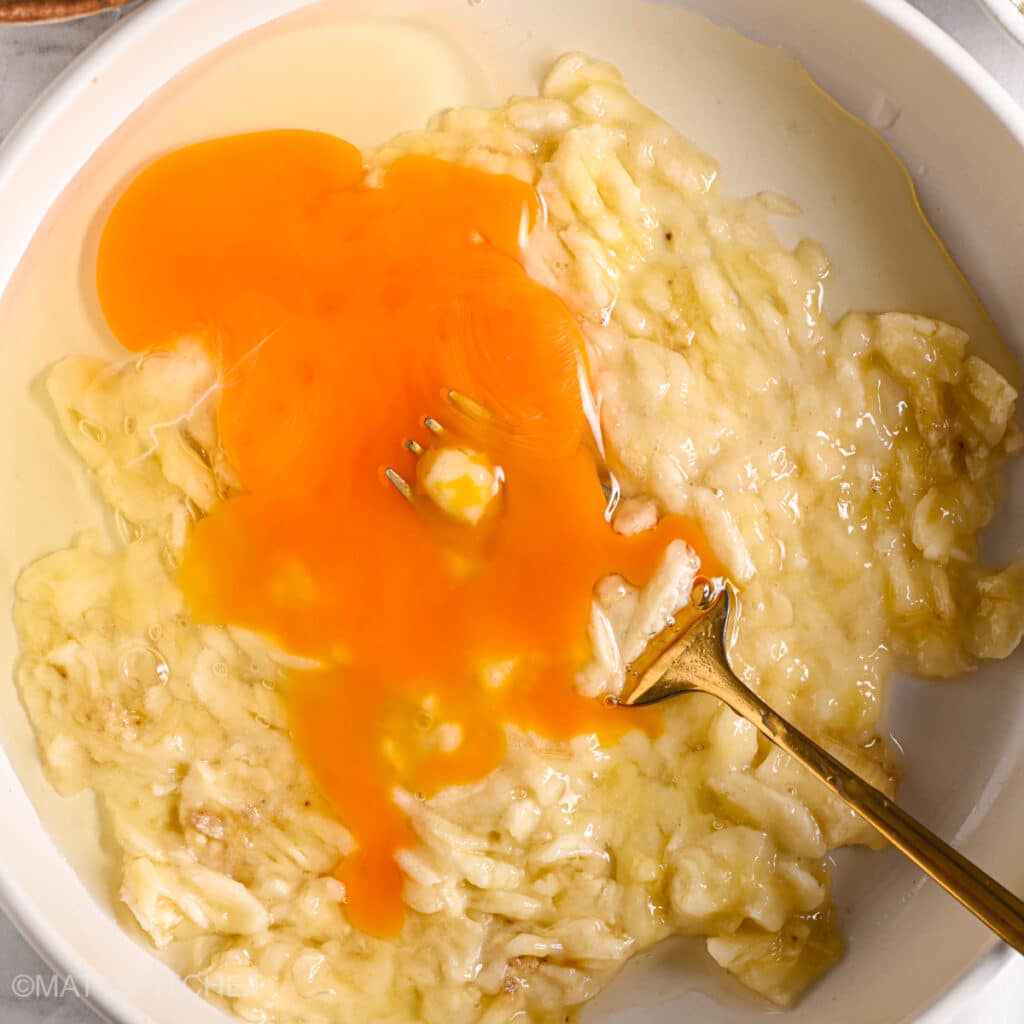 Adding eggs to mashed bananas for cake batter