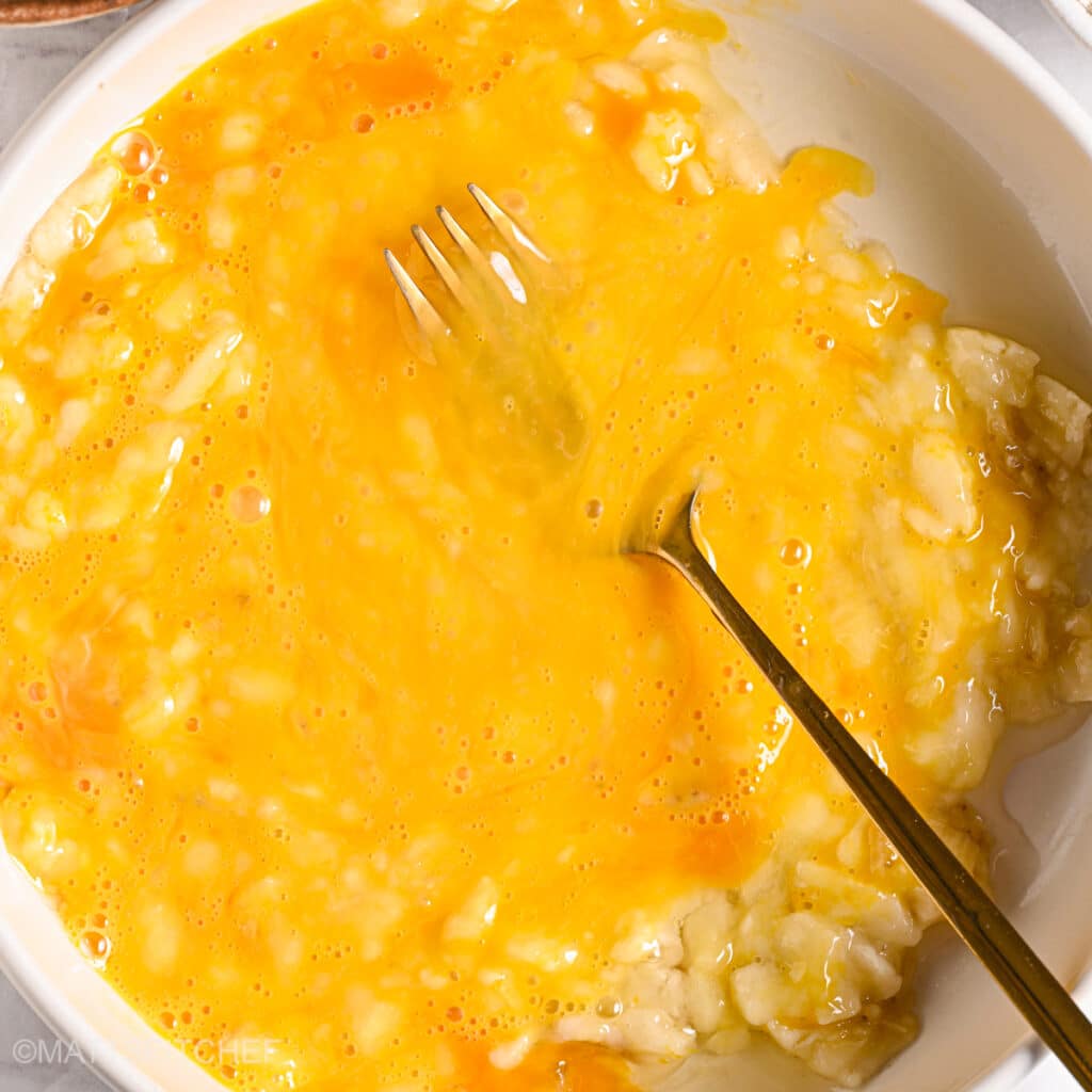 Whisking eggs and mashed bananas together in a bowl