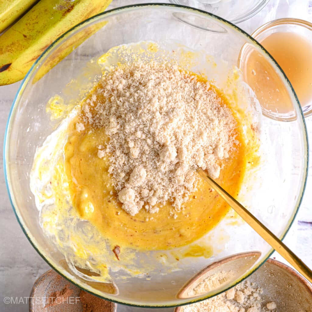 Adding blanched almond flour to mashed bananas and wet ingredients, to make banana bread batter.
