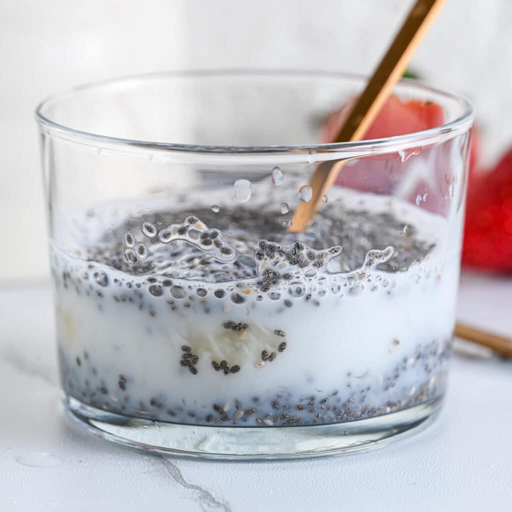 Mixing chia seed pudding with a golden spoon to break clumps