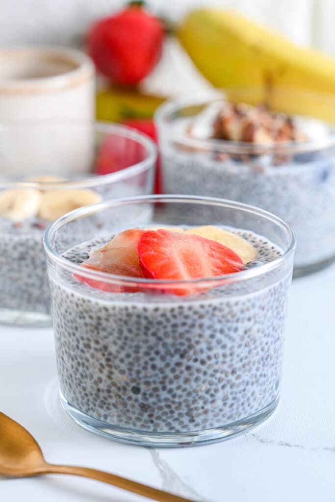 Easy chia seed pudding recipe served in glass jars with banana, strawberries, and crunchy toppings, ideal for vegan meal prep