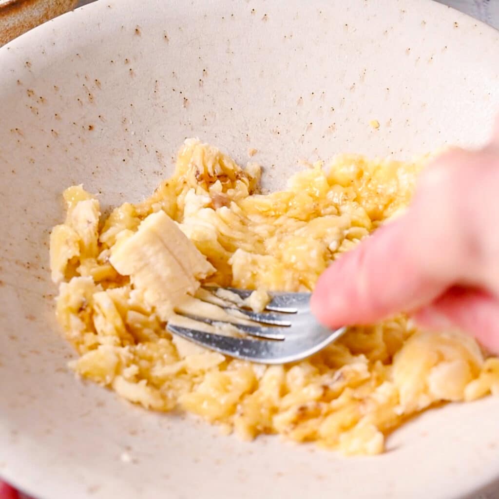 Mashing bananas with a fork until pureed