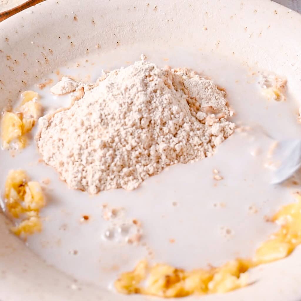 Adding milk to mashed bananas and flour to make easy banana bread moist