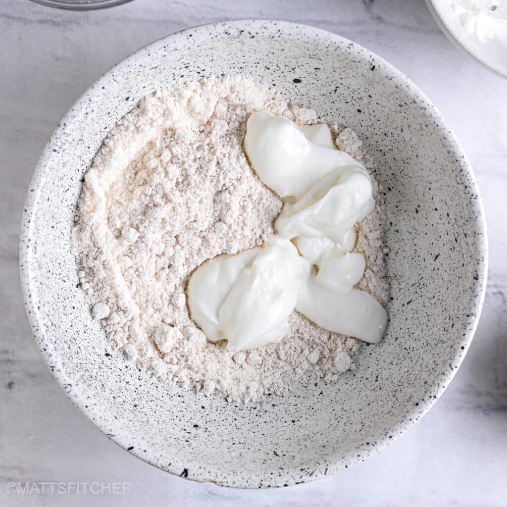 Oat flour and Greek yogurt in a bowl before mixing.