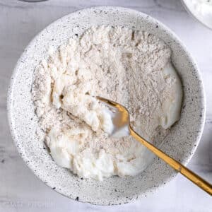 Mixing oat flour with Greek yogurt and maple syrup into a smooth batter before adding egg whites for pancakes.