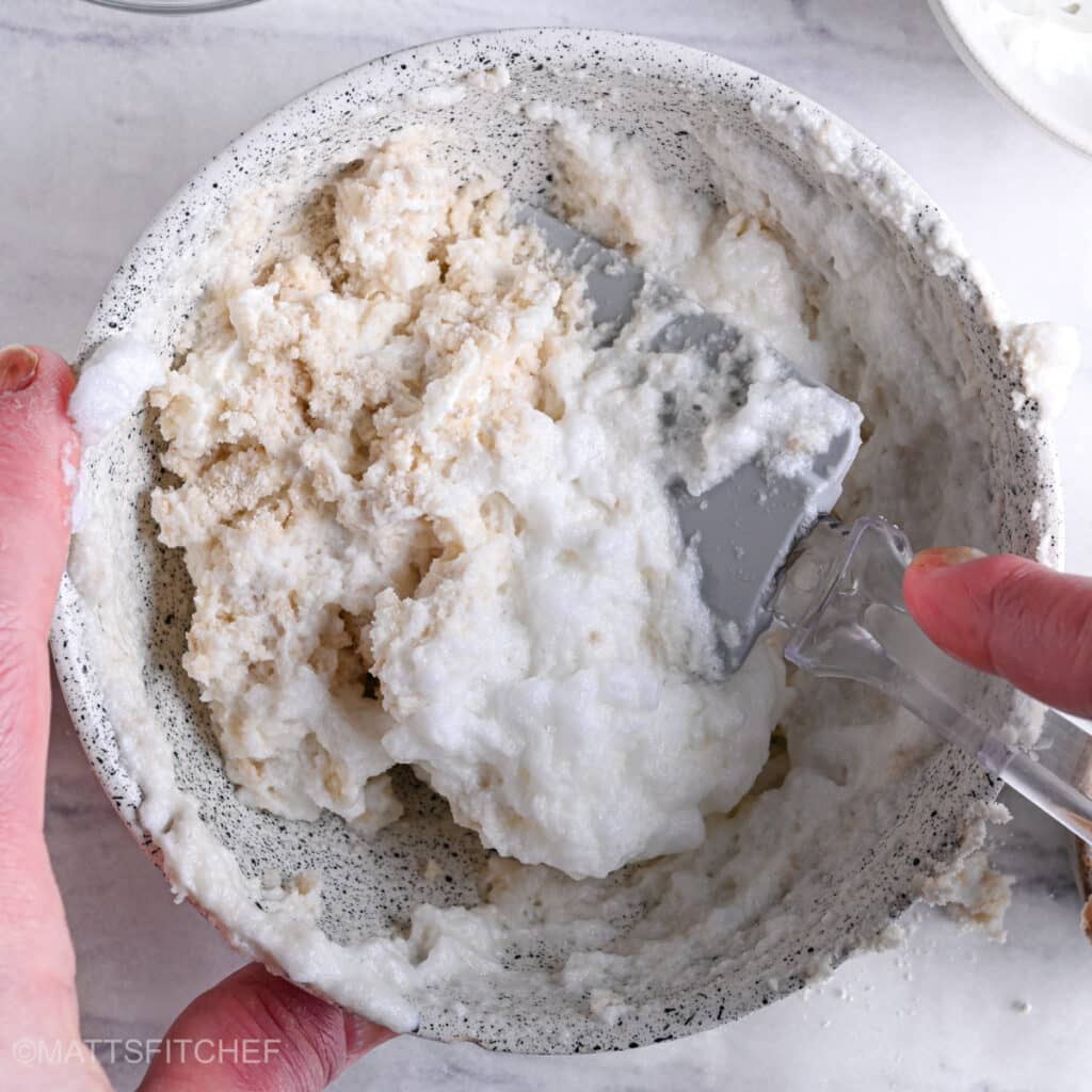 Folding in the batter beaten egg whites with a rubber spatula.