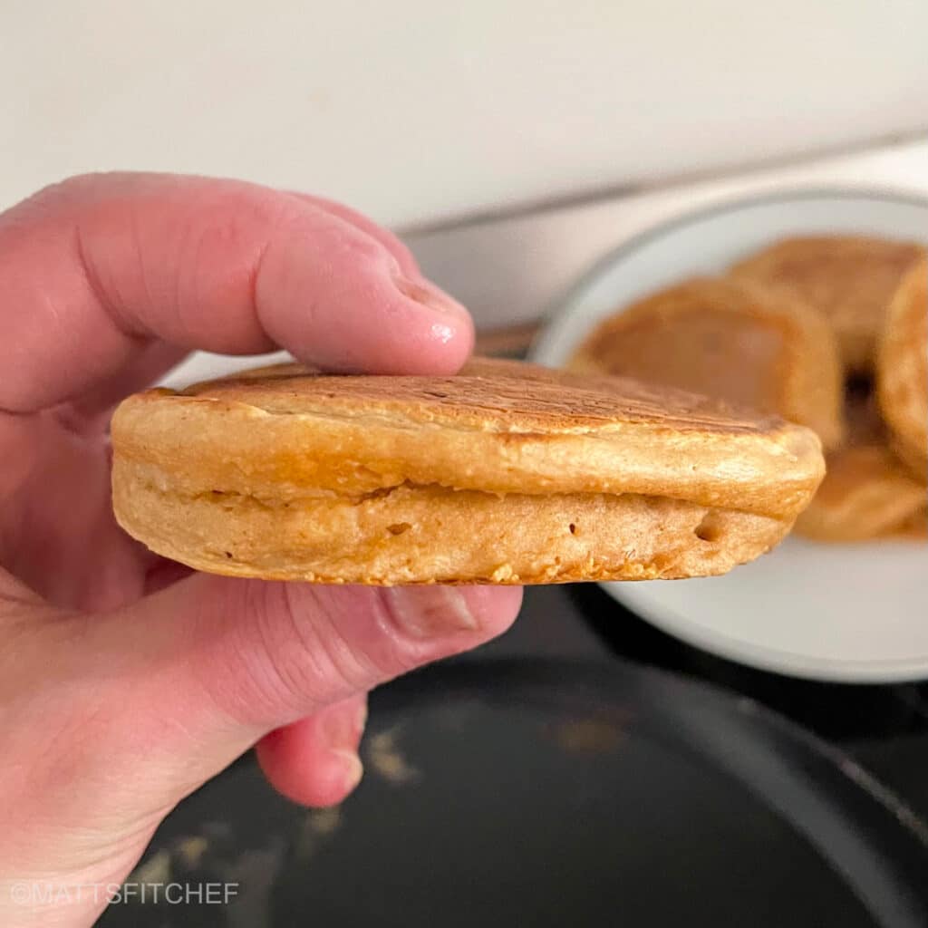 Holding fluffy egg white pancakes in the hands to show its extra fluffy texture.