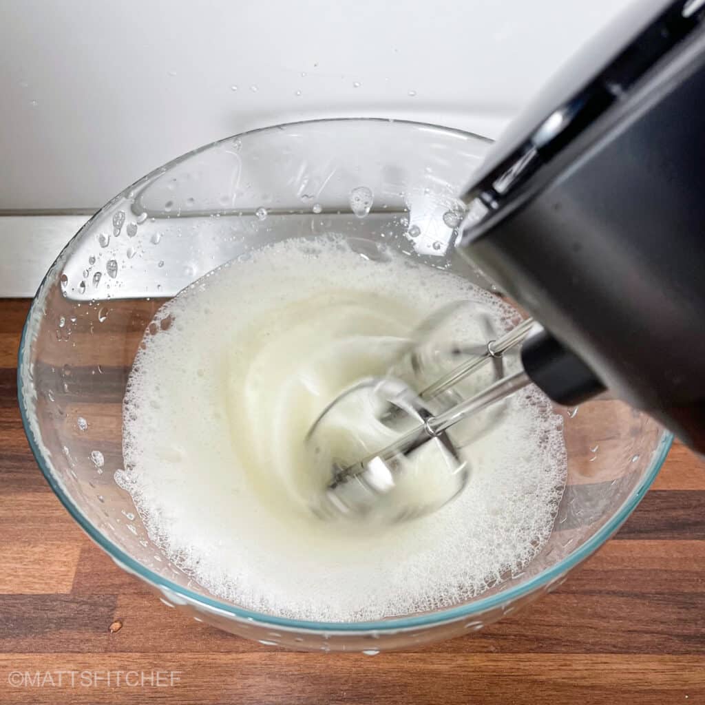Beating egg whites with electric mixer before adding them to pancake batter.